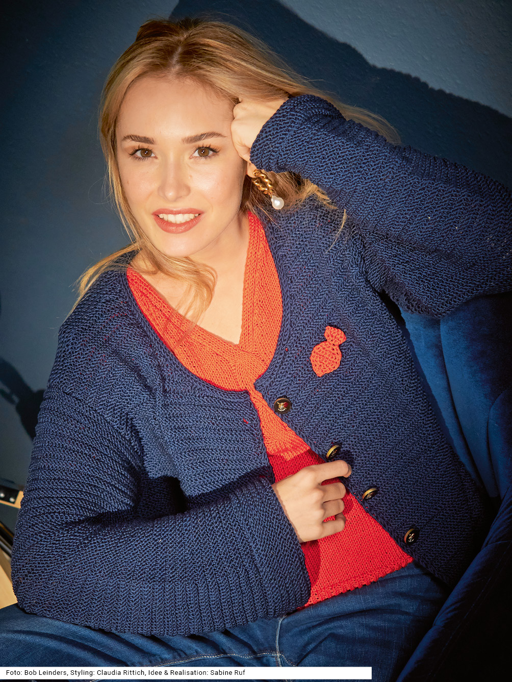 Modellansicht Bild 1: Marinefarbene Jacke mit Brosche und rotem, tailliertem Pulli