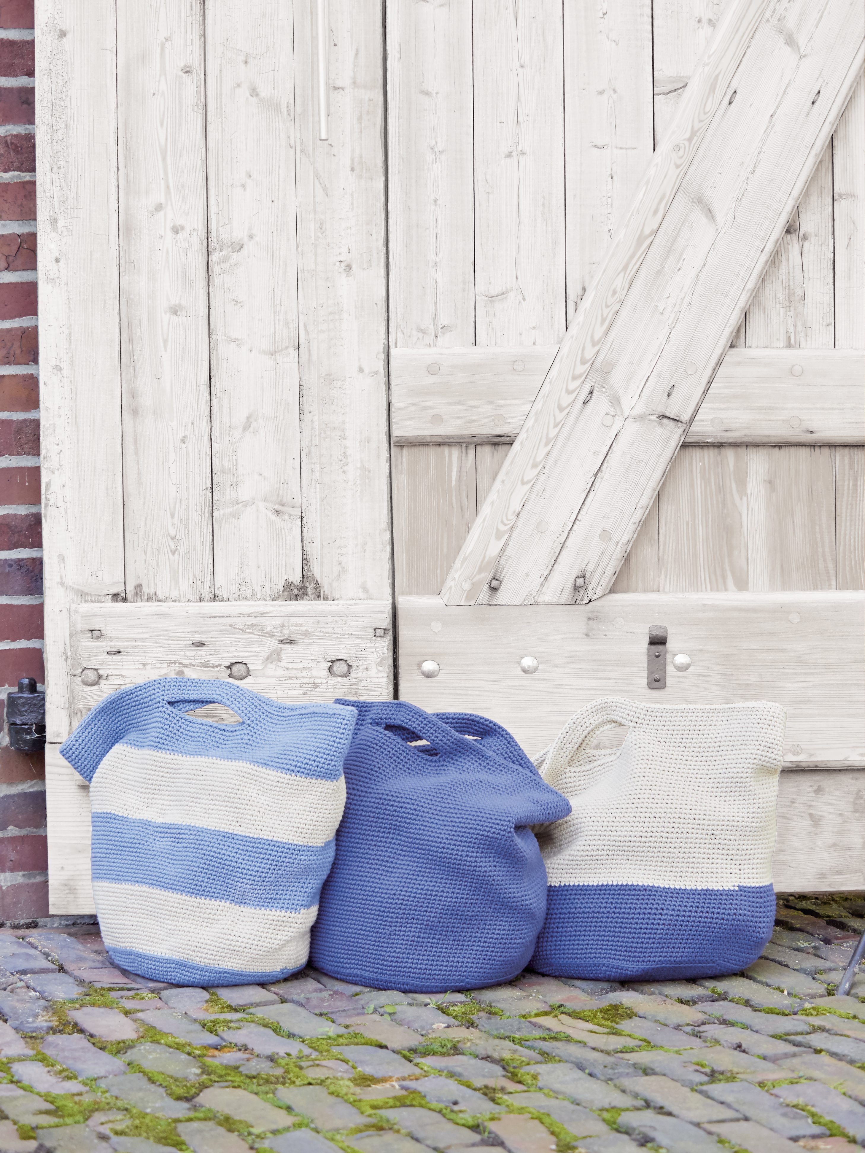 Drei gestrickte Taschen in Blau und Creme, mit Streifenmuster. Modisch, handgefertigt, DIY-Charme.