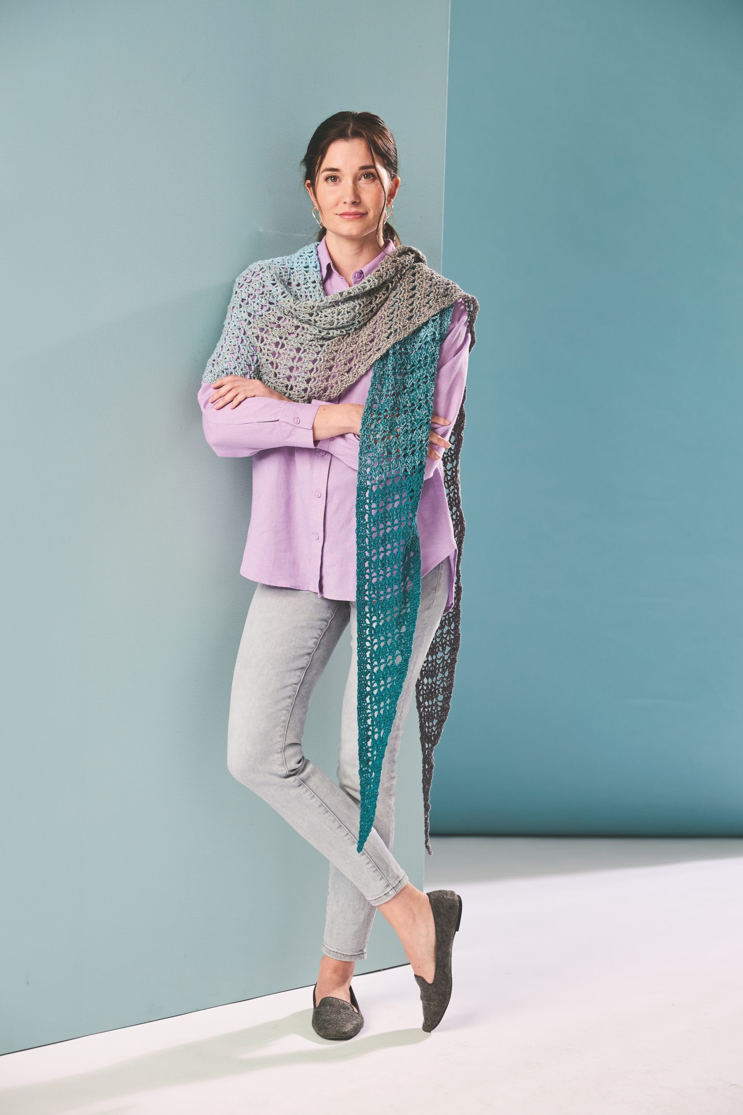 Modisches, gehäkeltes Dreieckstuch in Blau-Grau über lila Hemd und graue Jeans. Handarbeit, DIY.