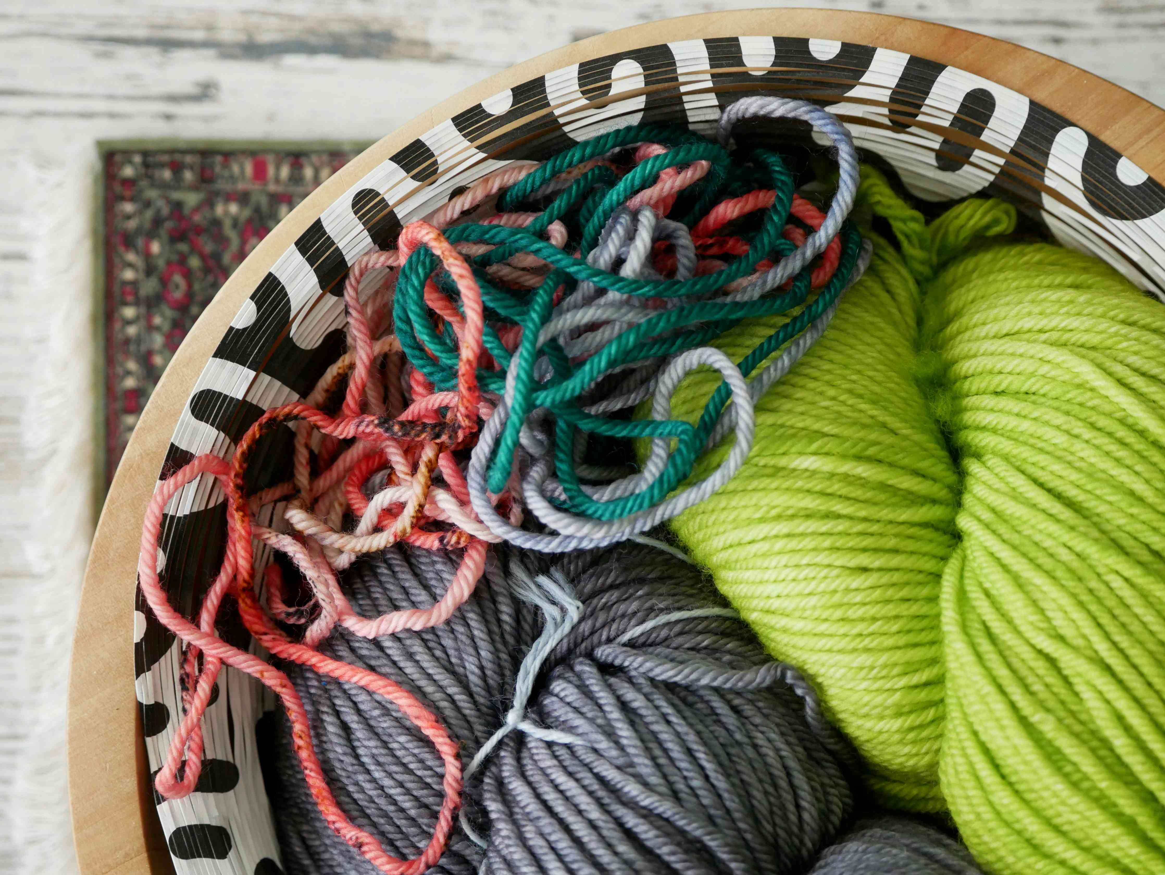 Leuchtende Garne, grün und grau in einer stilvollen Schale. Handarbeit, DIY Flair. Muster: Streifen, mehrfarbig.