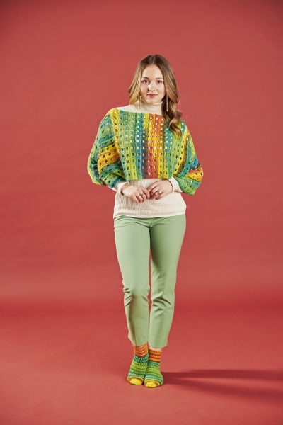 Farbenfroher, handgemachter Pullover mit Häkelmuster. Grüne Hose, bunte Socken. Modisch und kreativ.