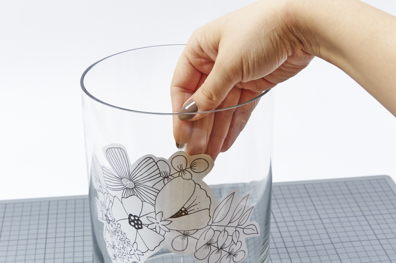 Klare Vase mit handgemachter, schwarzer Blumenverzierung. Schlicht und elegant für modische Innenräume.