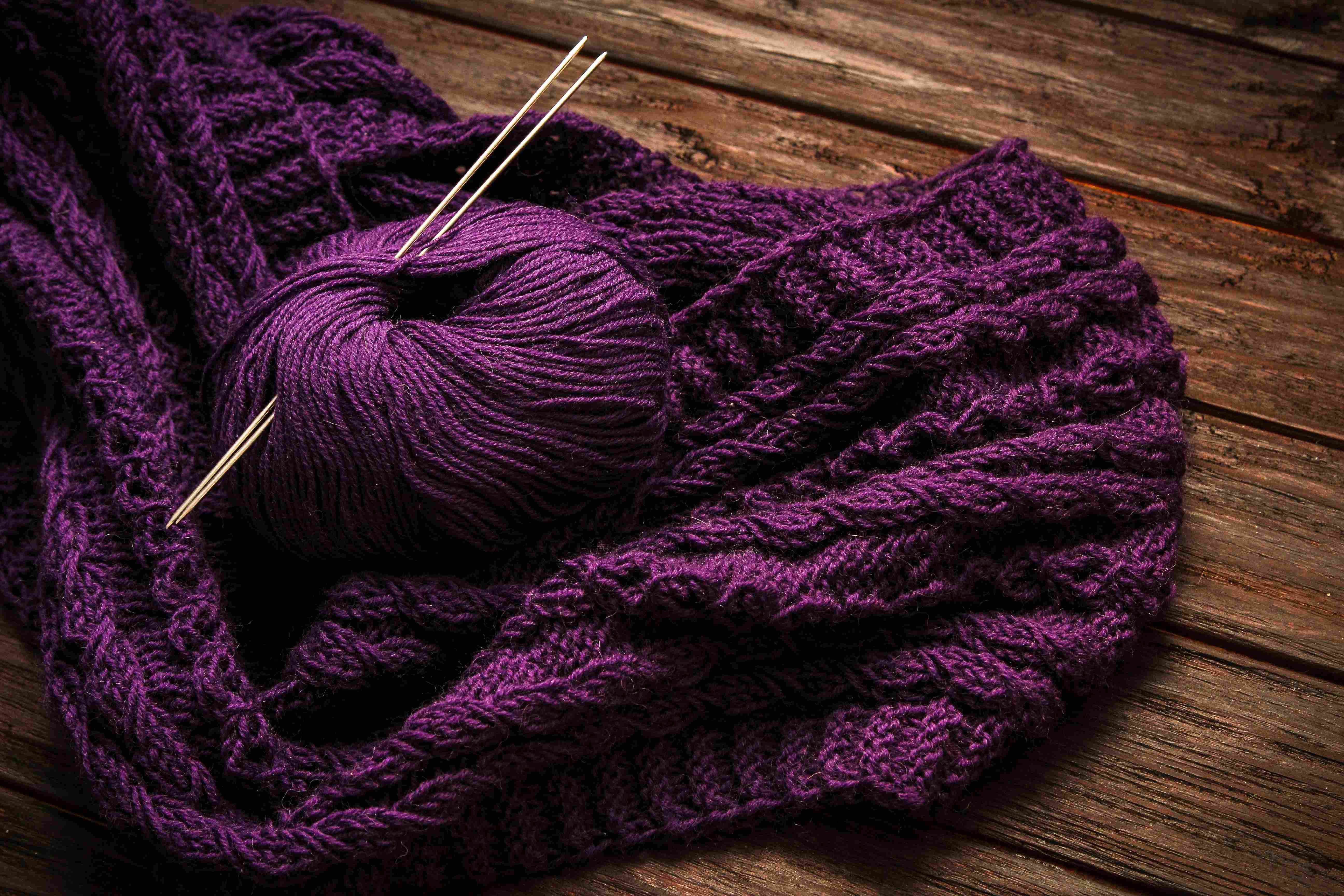 Foto von Oksana Zub auf Unsplash Tiefviolette, handgemachte Strickware; komplexe Muster; DIY mit Nadeln. Modisch, kreativ und einzigartig.