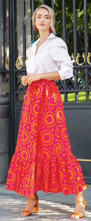 Langes, rotes Boho-Rock mit gelben Mustern, kombiniert mit weißer Bluse. Farbenfroh, modisch, elegant.