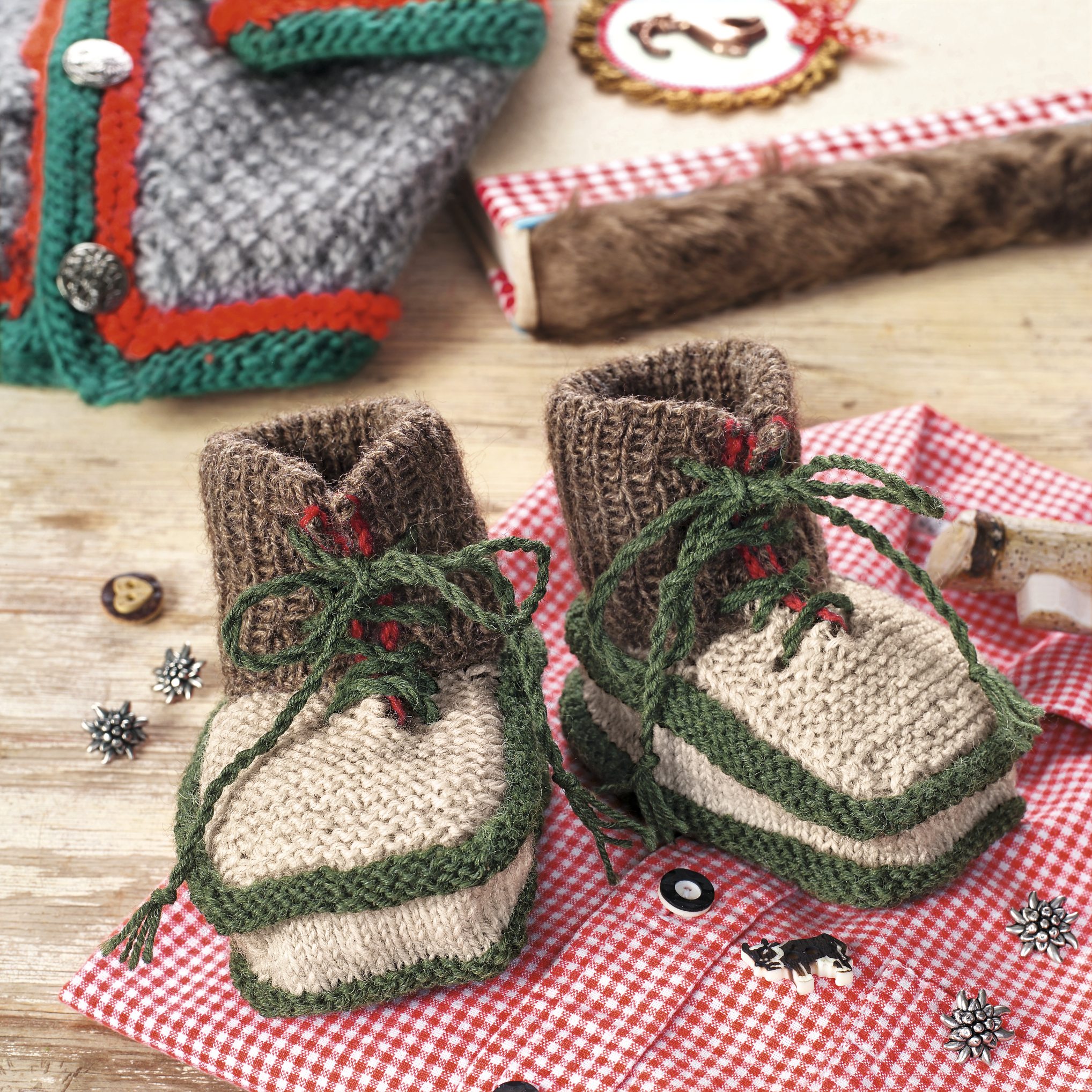 Selbstgemachte, gestrickte Babybooties in Beige mit grünen Details und Schnüren. Ideal für modische DIY-Enthusiasten.