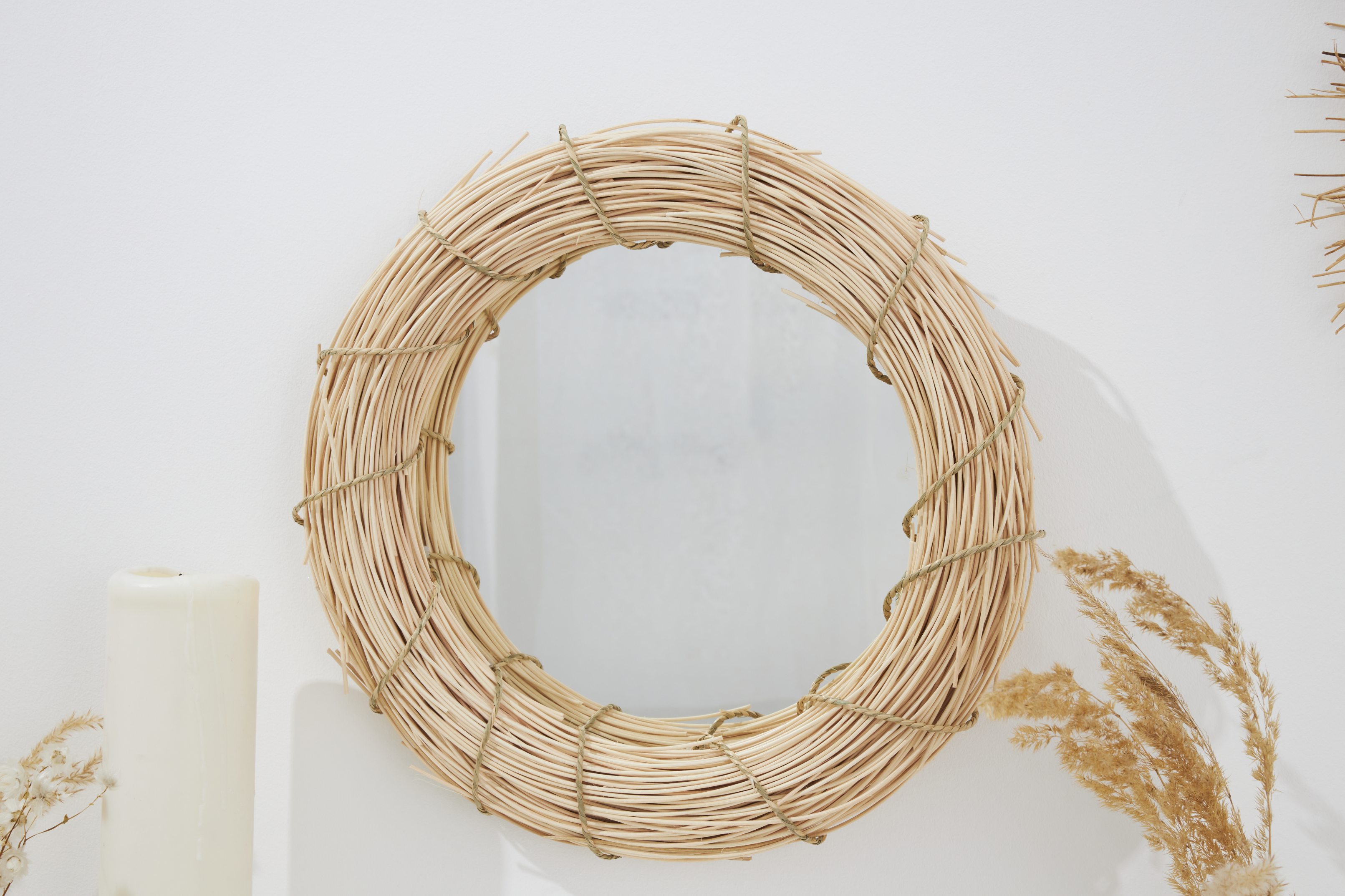 Runder Spiegel mit geflochtenem Rattanrahmen. Natürliche Töne, handgemacht, rustikales Design.