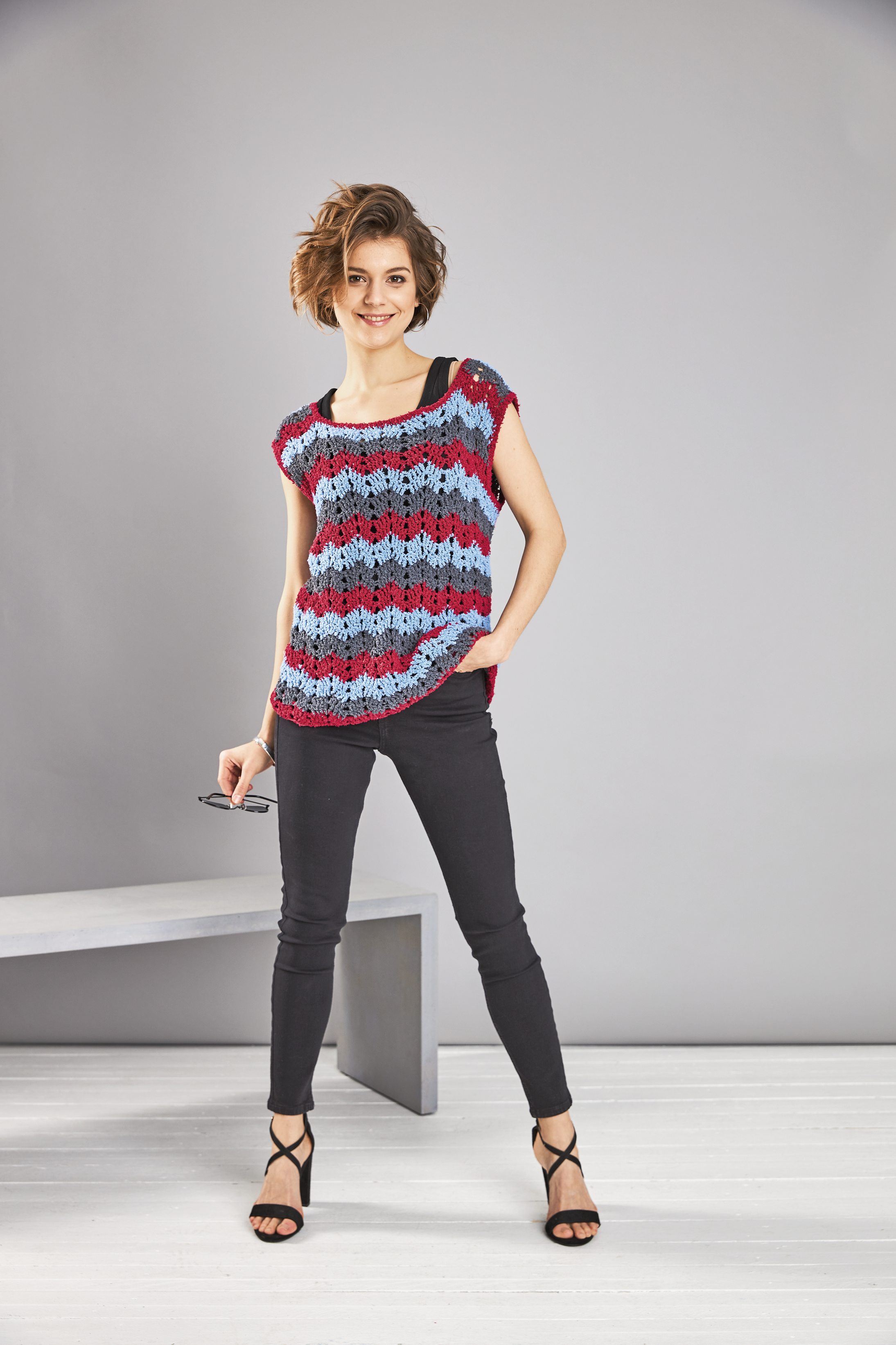 Handgemacht aus bunten Lochmustern in Blau und Rot, lässiger Schnitt, DIY-Look. Stylische schwarze Hose.