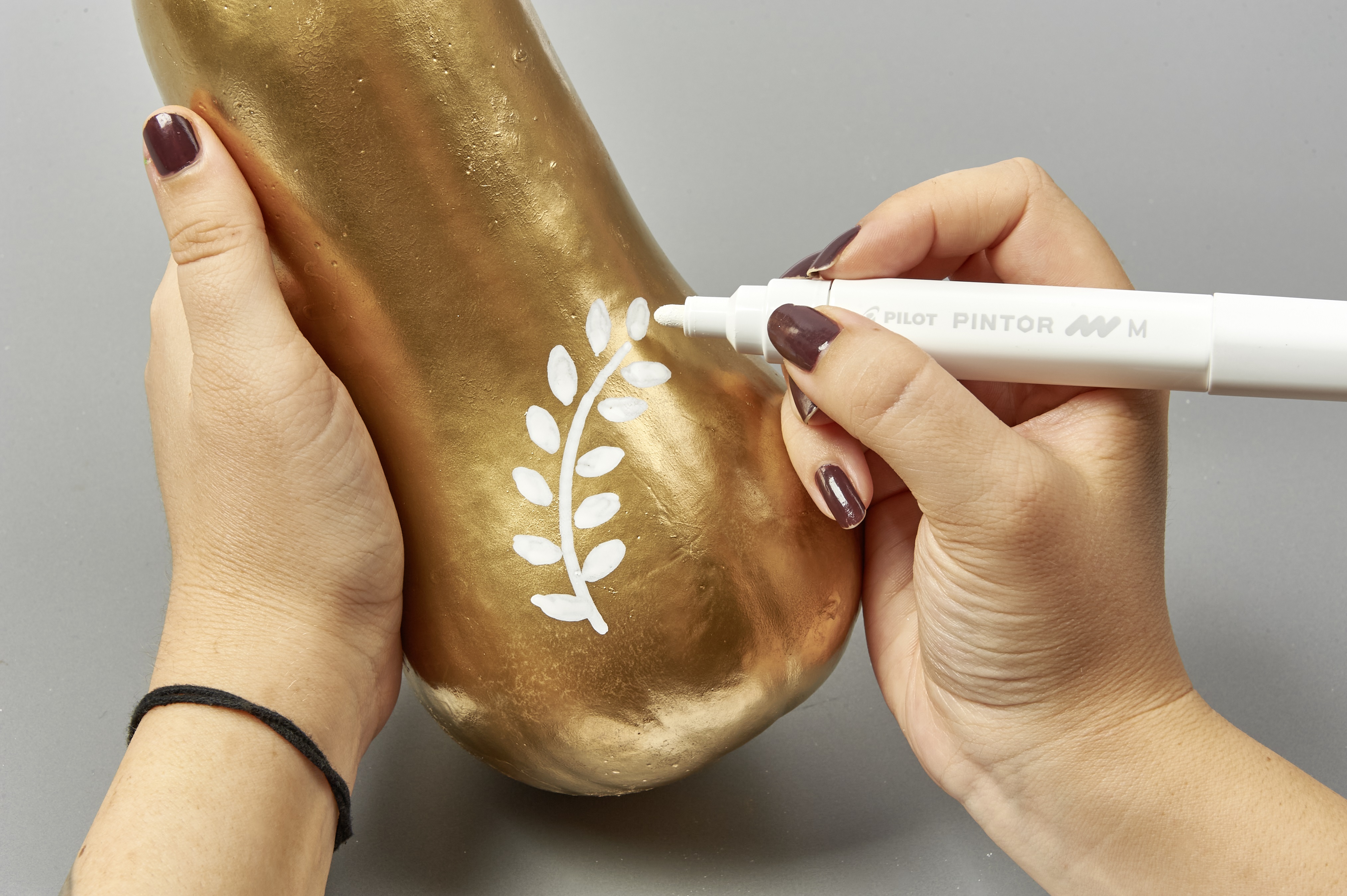 Goldener Kürbis mit weißem Blattmuster, handbemalt, modisch, selbstgemacht, kreatives DIY-Projekt.