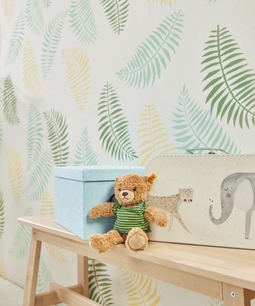 Spielzeugbär in grünem Streifenshirt; pastellfarbene Boxen, natürlicher Look; handgemachte Details.