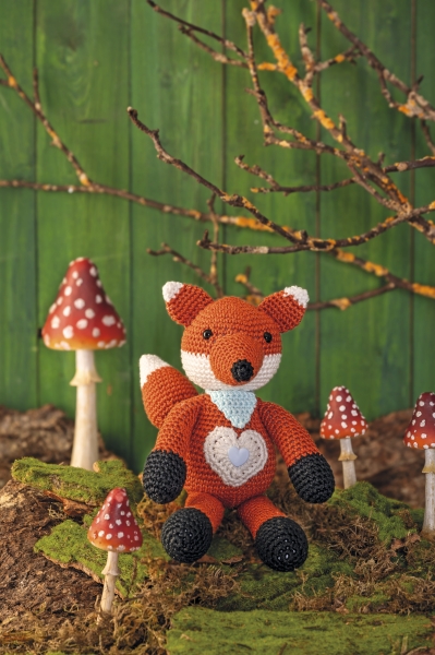 Selbstgemachter Fuchs aus Wolle, warmes Orange, süßes Herzmuster, modische Handarbeit, detailreich.