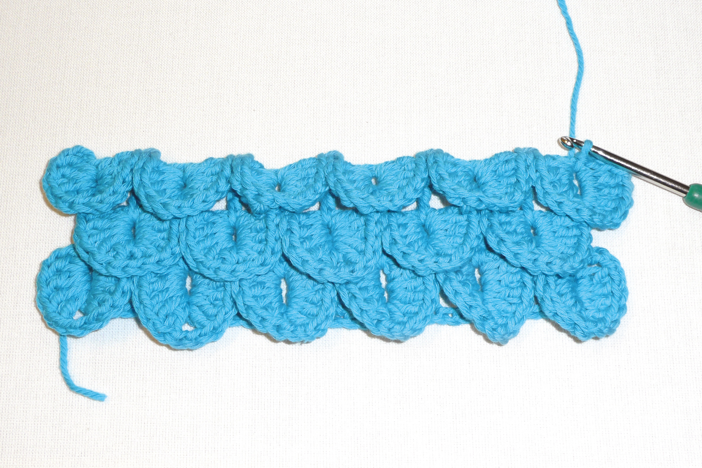 Leuchtend blaue, gehäkelte Wellen. Farbkräftig, selbstgemacht mit einzigartigem Strukturmuster. DIY-Kreativität.