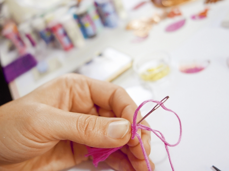 Hand näht mit pinkem Faden. Modische Handarbeit, kreativ und individuell gestaltet.