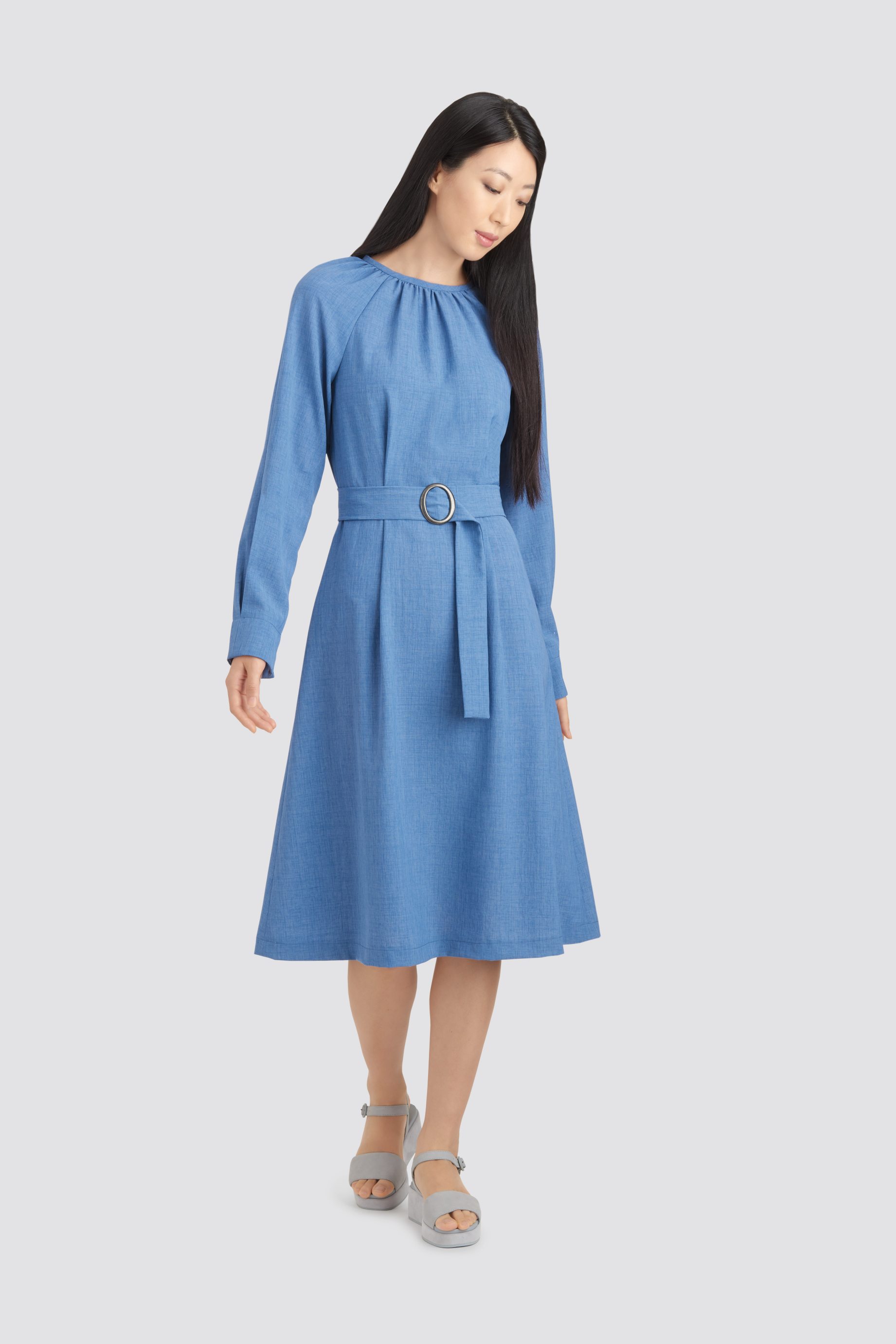 Azurblaues, knielanges Kleid, betonter Gürtel, schlichter Schnitt, langärmlig, zeitlos und stilvoll.