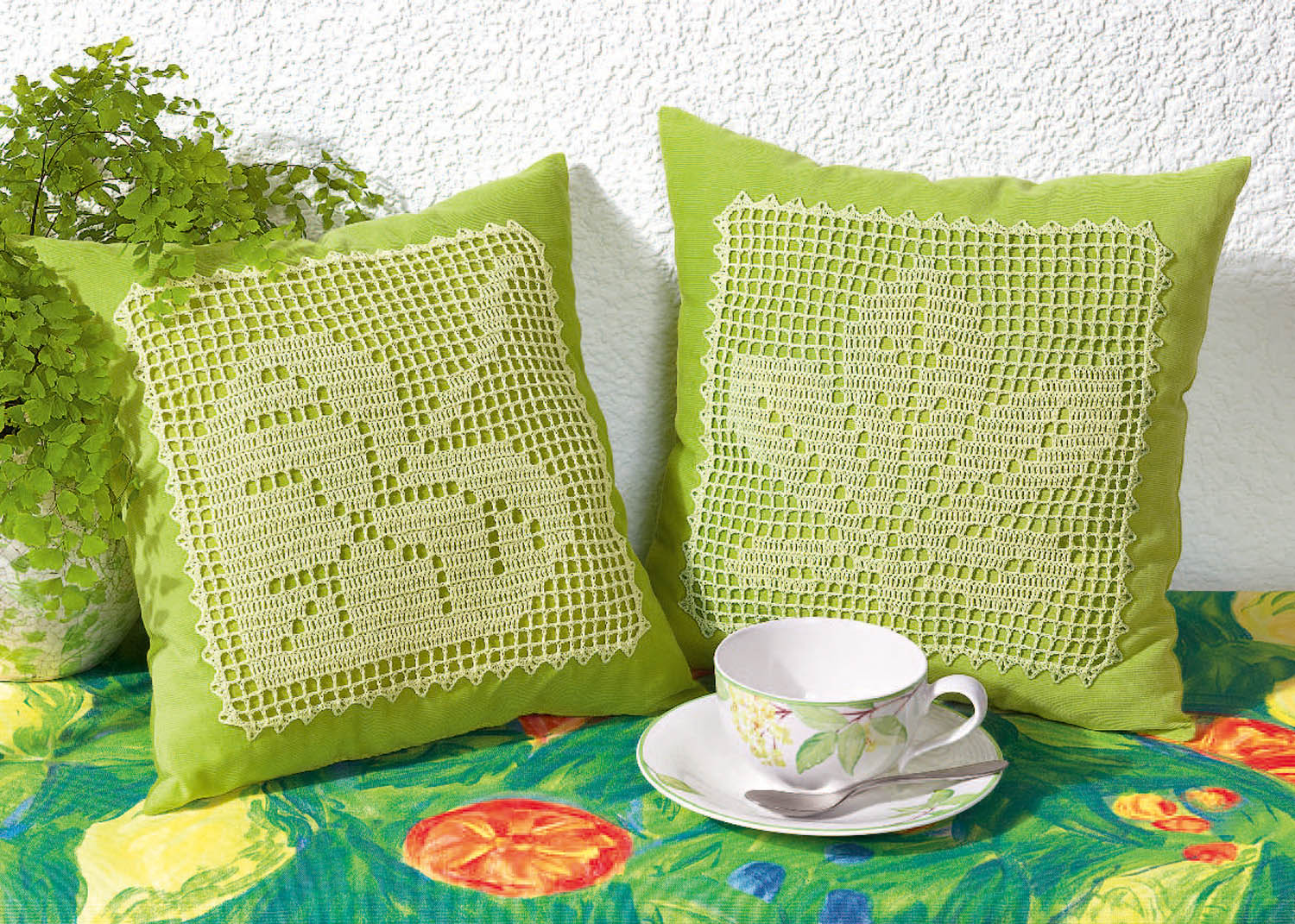 Grüne Kissen mit cremefarbenen Häkelmustern. Modisch, selbstgemacht, kunstvoll.