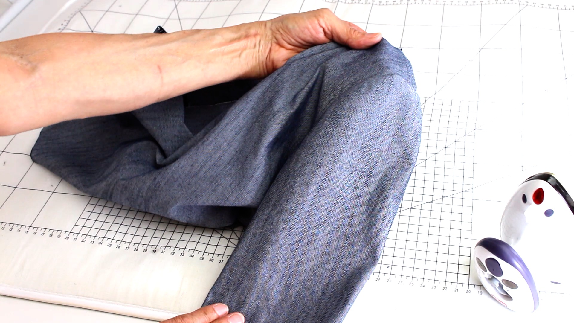 Hand hält modischen, blauen Jeansstoff. Schlichtes Design, ideal für selbstgemachte Projekte. Handarbeit.