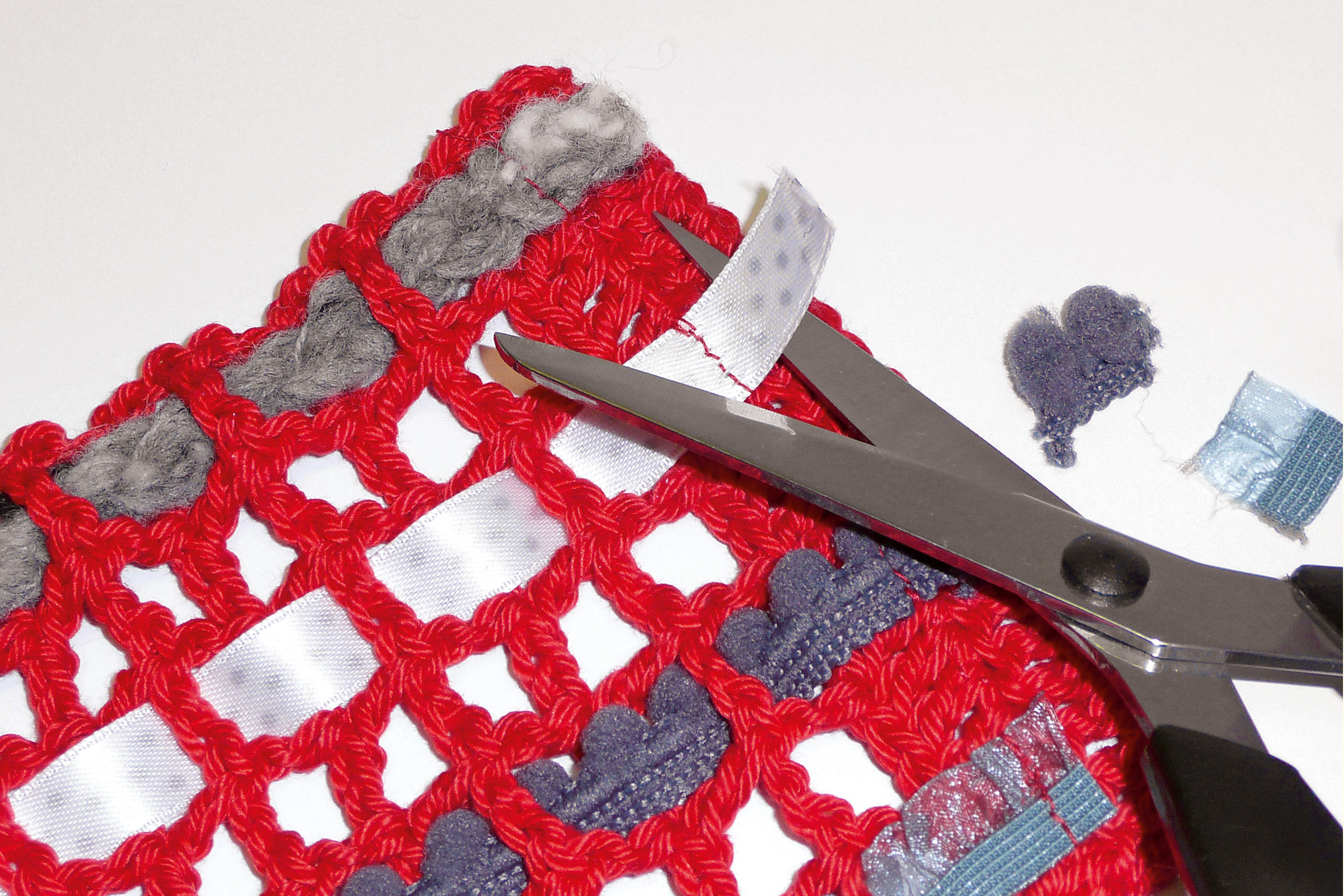 Rot gehäkeltes Netz mit grauen Akzenten & weißen Bändern. Handgemacht, DIY, modisch, geknotete Struktur.