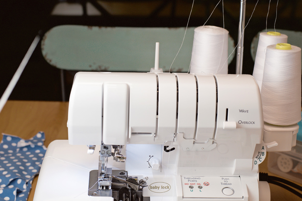 Weiße Overlock-Nähmaschine, DIY-Projekt. Blaue Polka-Dot-Stoffe, ideal für handgemachte Mode.