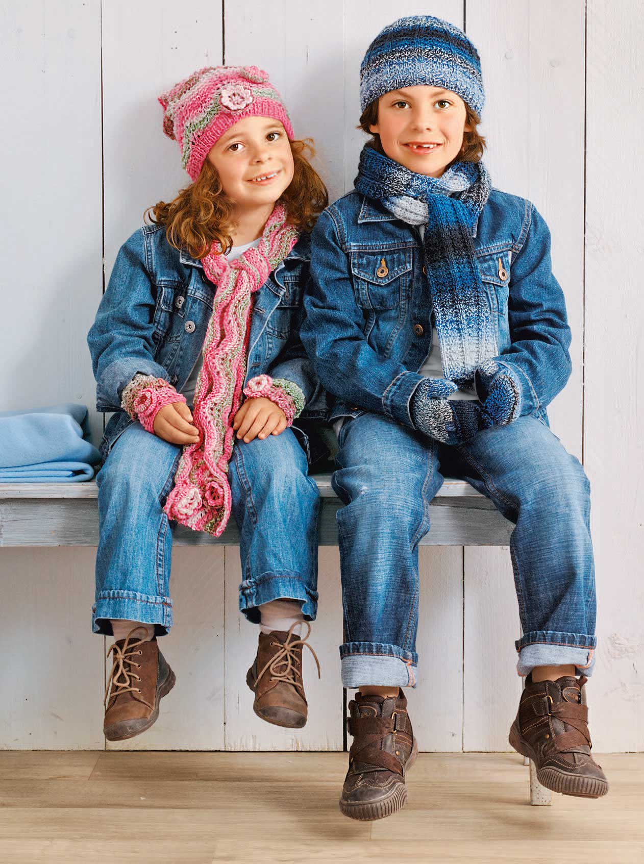 Modisches Denim-Outfit mit handgemachten, farbenfrohen Strick-Accessoires: rosa Schal, Mütze; blau-weiße Armstulpen.