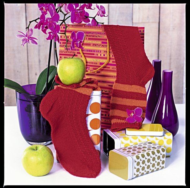 Handgestrickte rote Socken mit Streifenmuster und Blütenapplikation; DIY, modisch.