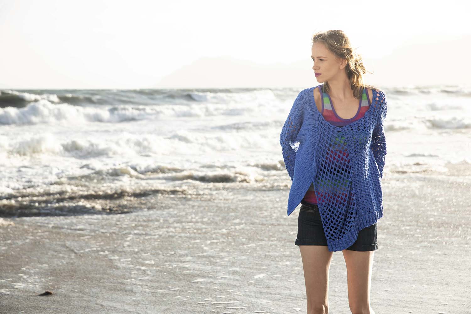 Blauer, handgemachter Häkelpulli, netzartig; über gemustertem Top, lässig geschnitten, modisch und sommerlich.