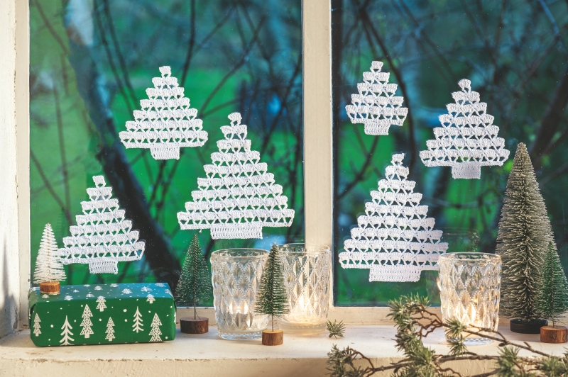 Weiße, handgemachte Tannenbaum-Aufkleber mit zarten Mustern sorgen für modisch-festliche Fensterdeko.