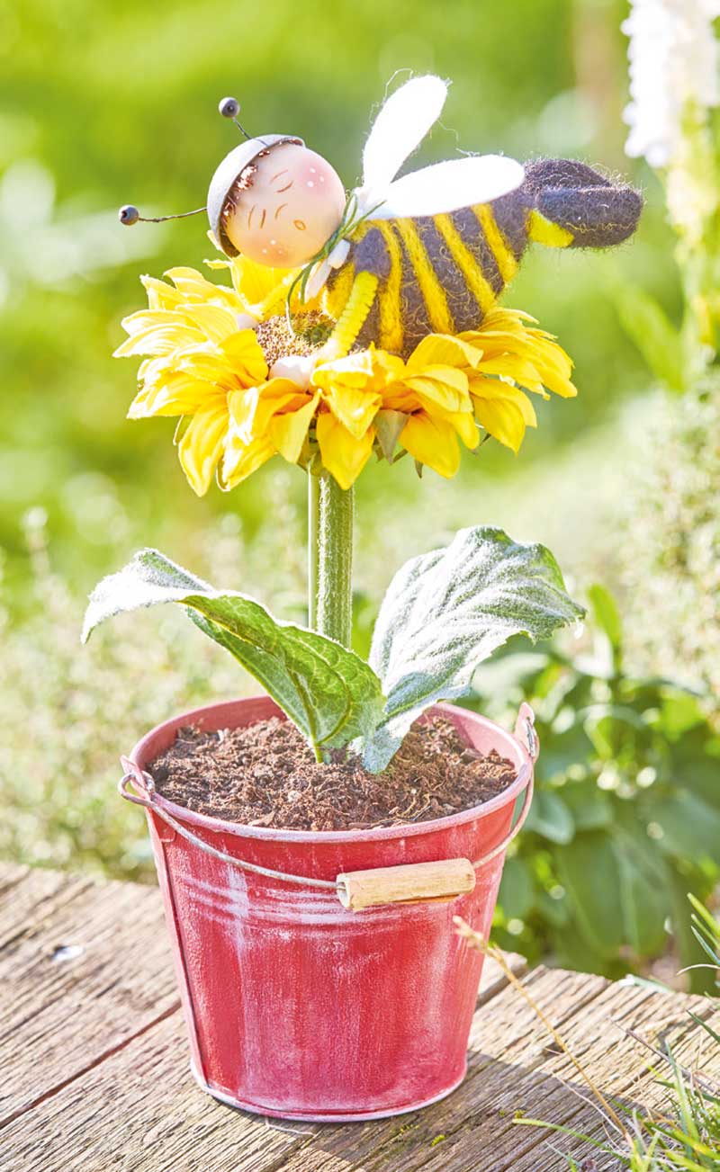 Handgemachte Biene aus Filz, modisches Streifenmuster auf gelber Blüte in rustikalem Topf.
