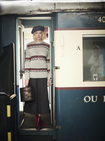 Strickpulli mit geometrischen Mustern, grauer Rock, rote Stiefel, schwarze Baskenmütze; vintage und chic.
