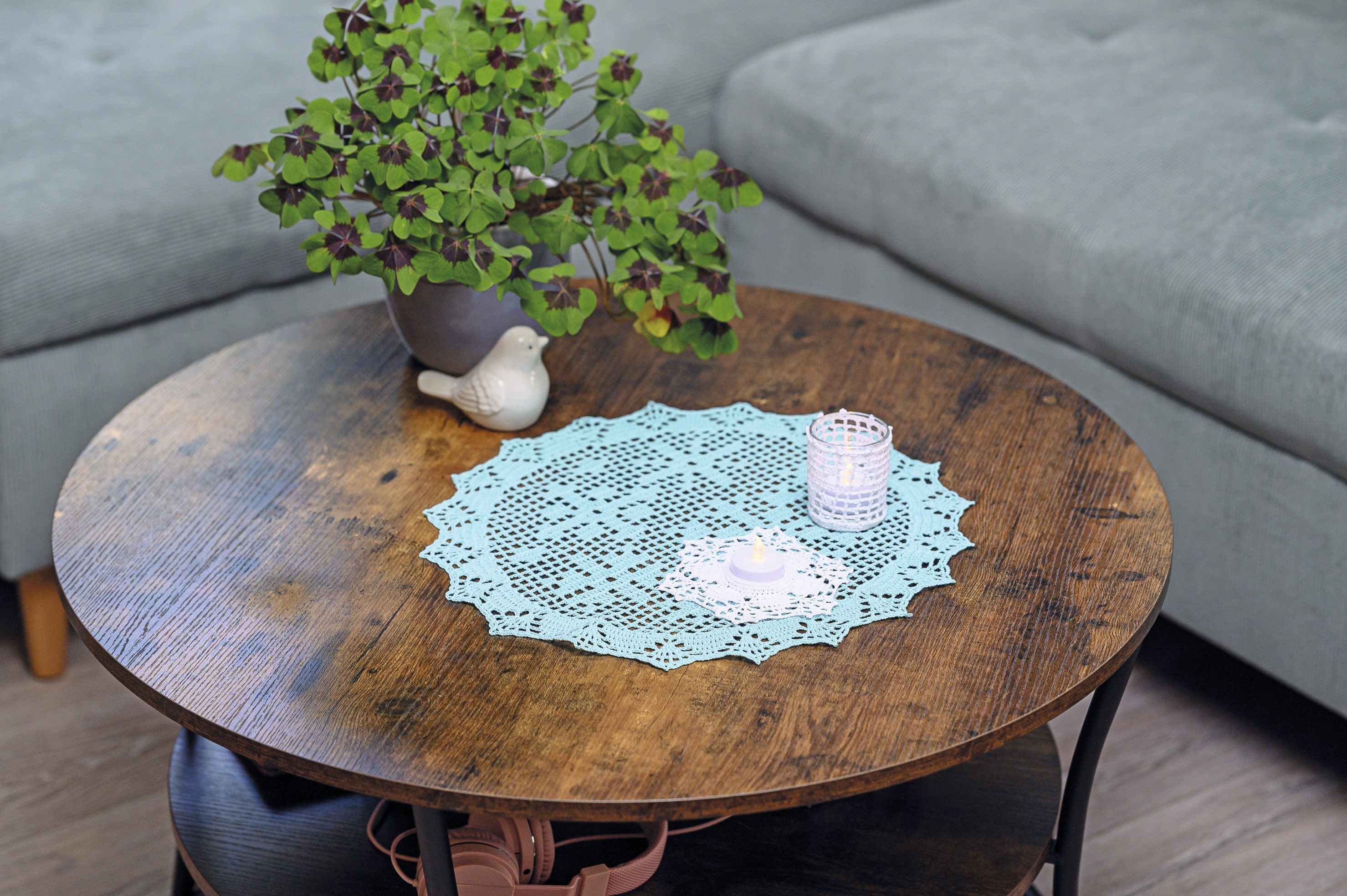 Hellblaues, rundes Häkeldeckchen mit zartem Muster. Modisch und handgefertigt, ideal für DIY-Dekoration.