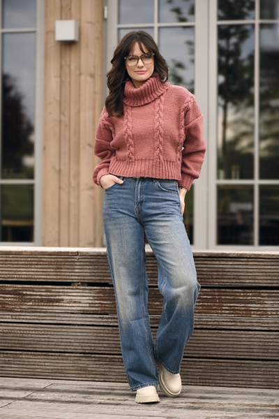 Modischer Strickpullover in Altrosa, Zopfmuster, Rollkragen, kombiniert mit lässigen, ausgewaschenen Jeans.