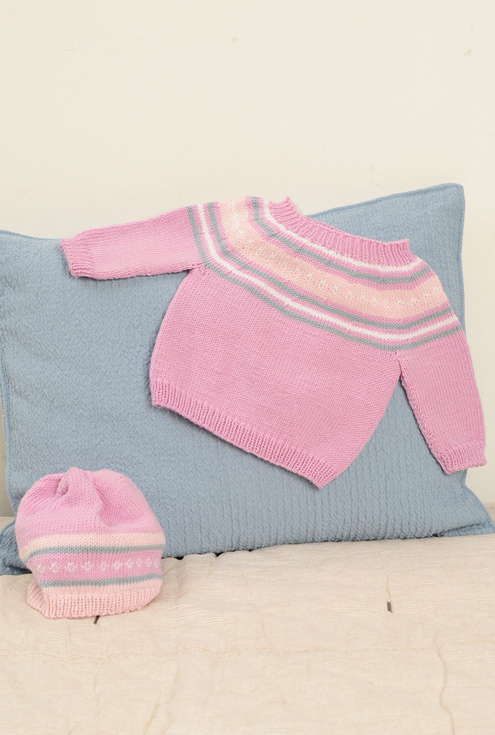 Beigefarbene Jacke  und rosafarbener Pulli mit Mütze