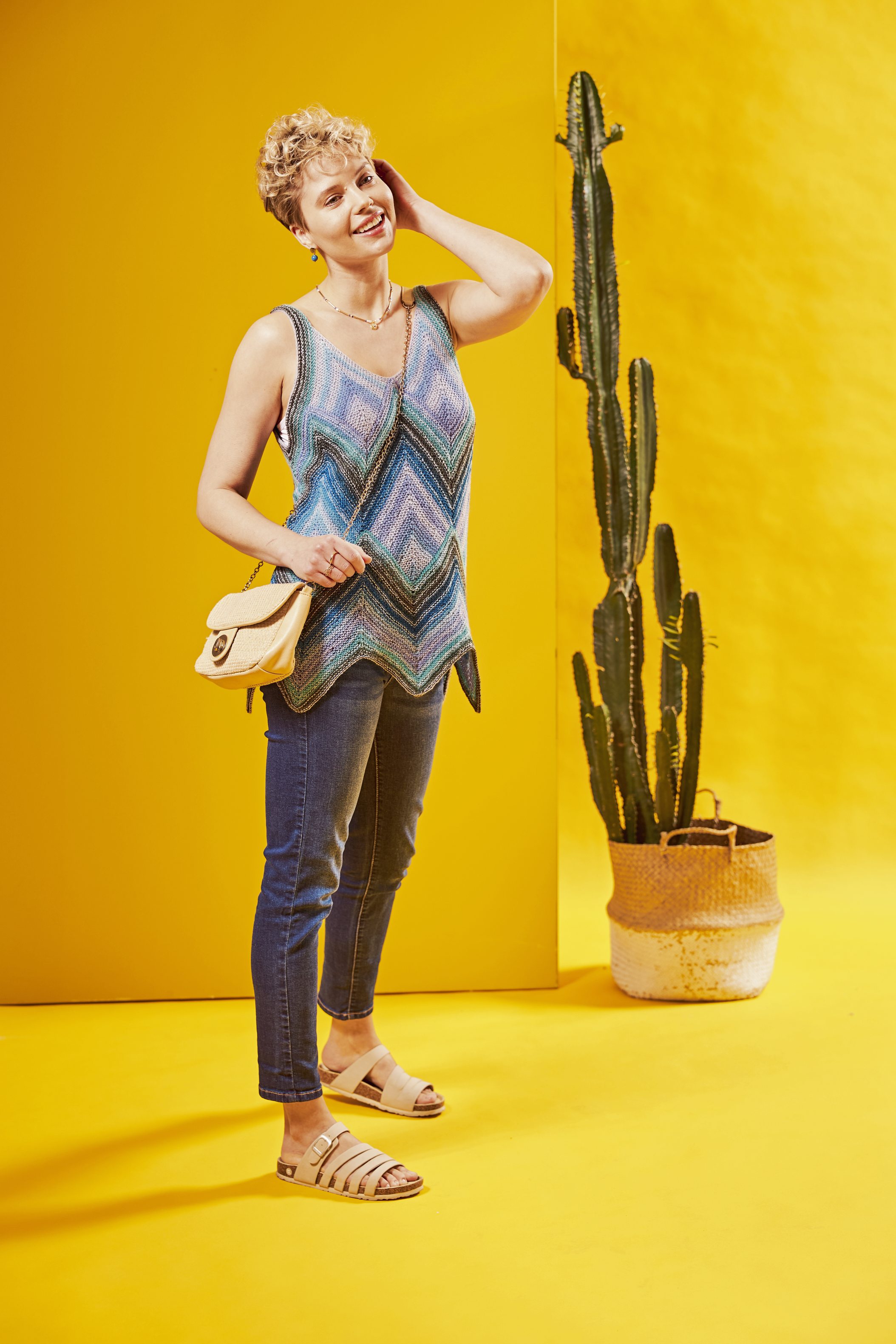 Buntes Chevron-Top, ärmellos, handgemacht. Eng anliegende Jeans, beige Sandalen. Lässiger Stil.