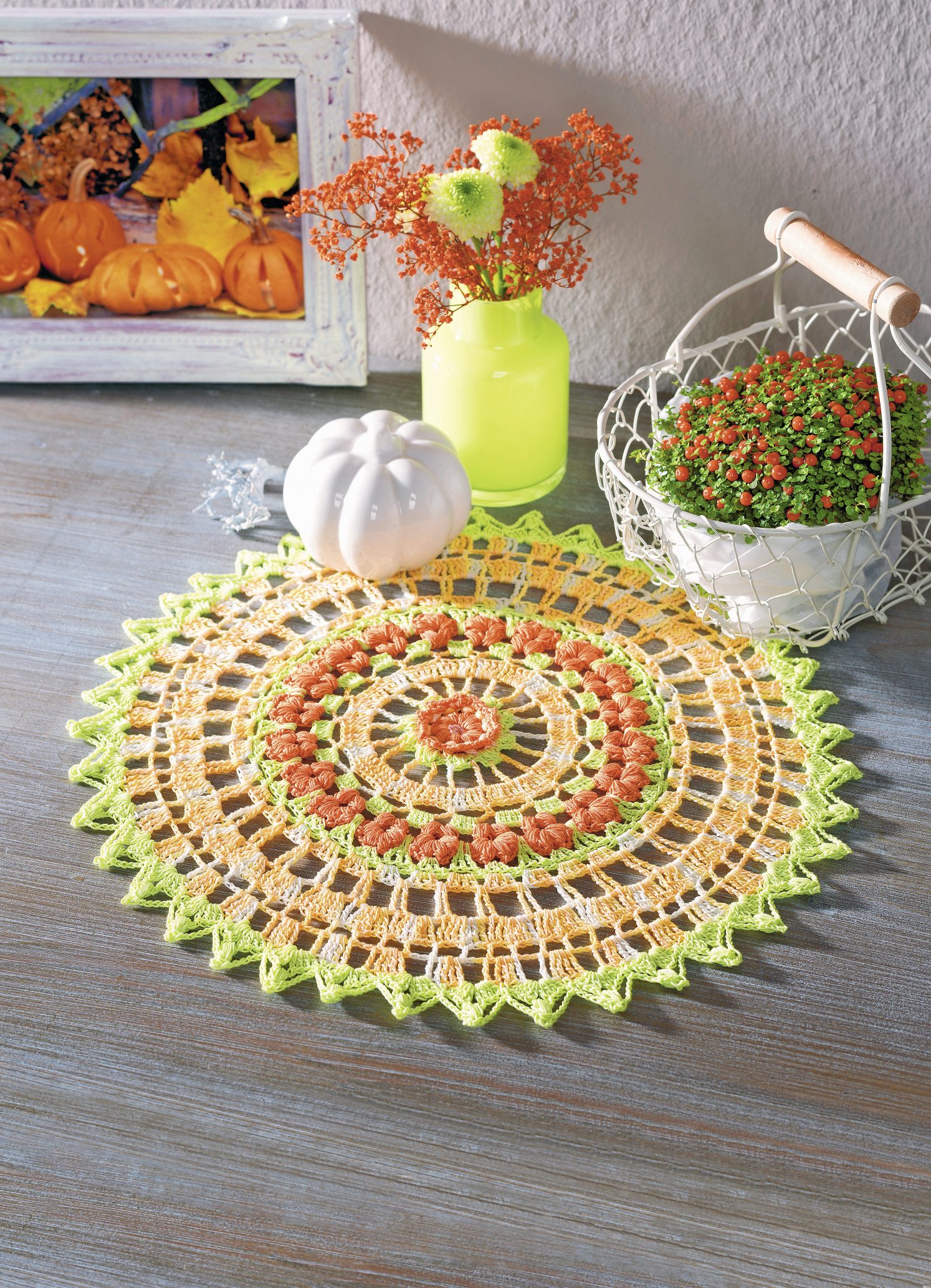 Runde, handgemachte Häkeldecke in Herbstfarben. Geflecht aus Orange, Gelb und Grün; kunstvoll und modisch.
