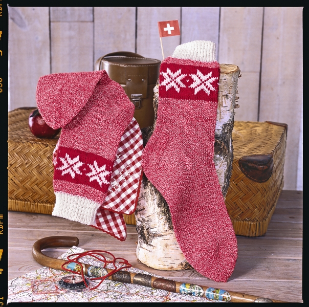 Rote, handgemachte Socken mit weißen Schneeflockenmuster, elastischem Bündchen und traditionellem Design.
