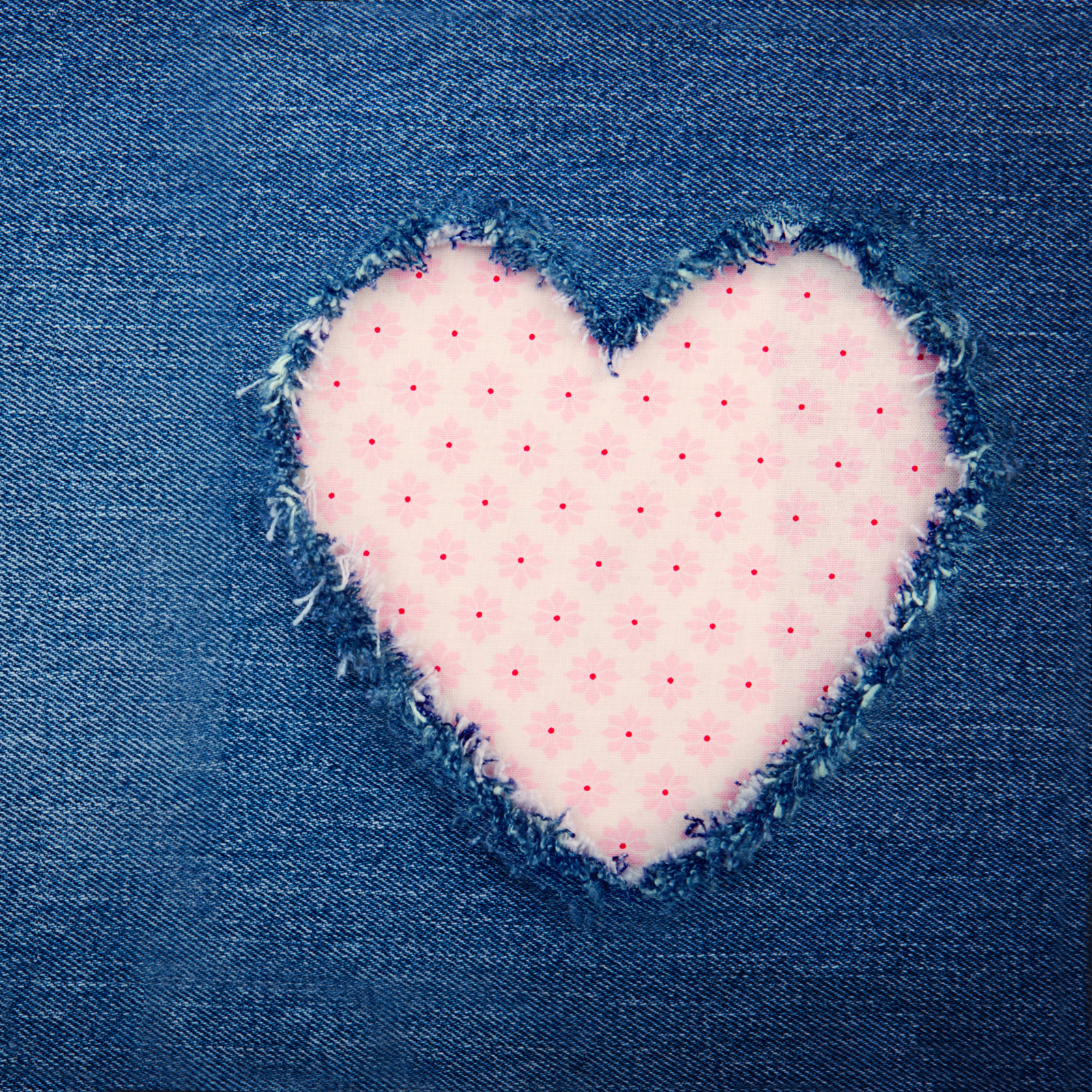 Jeansstoff mit ausgefranstem Herz-Patch. Rosa, zartes Muster. Handarbeit, DIY, modisch.